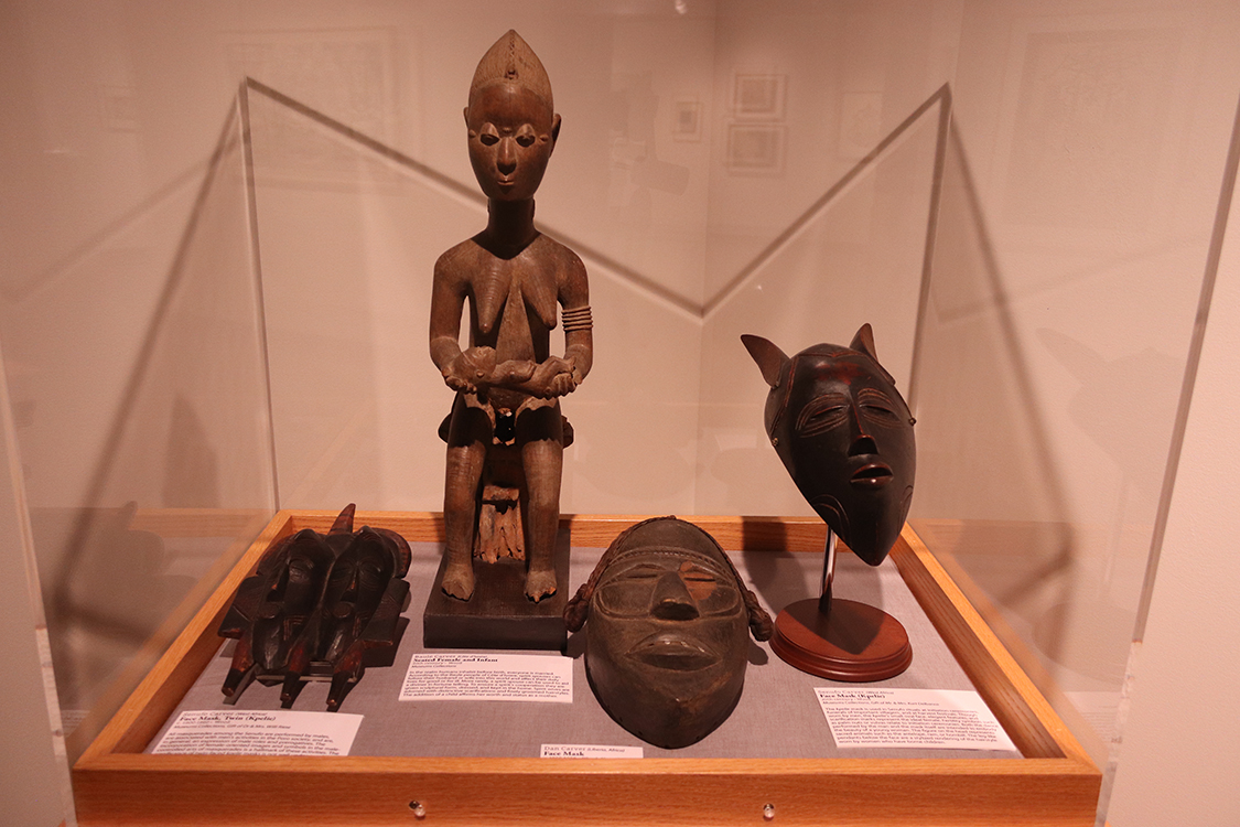 View of carved wood sculptures in display case.